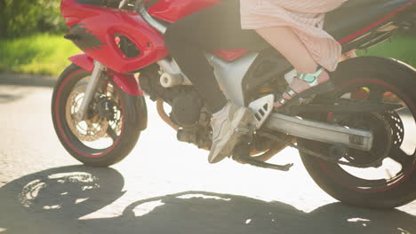 close-up view of two women riding a power bike in motion, the rider's legs are clad in sneakers, while the passenger wears sandals, with the gown fluttering in the wind as the bike moves