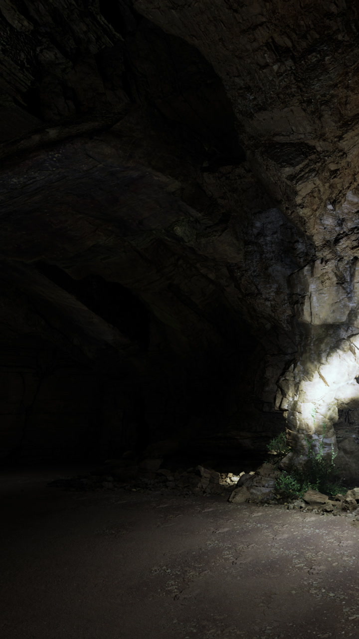 Light shines on rocks inside a dark cave during nighttime exploration