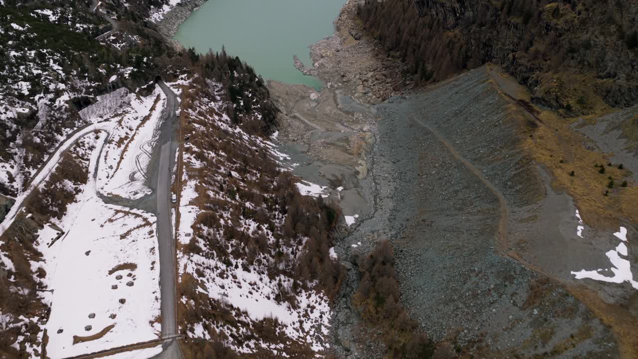 Lake With Mountain Views Partly Covered With Snow During Winter. - aerial tilt up shot