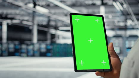 vertical video close up of admin in data center using green screen tablet