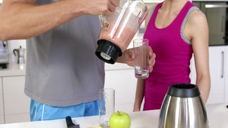 happy couple serving smoothie in a glass