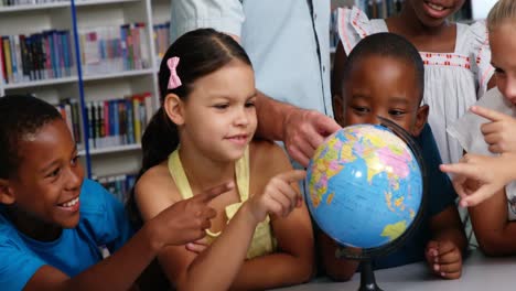 teacher discussing globe with kids in library