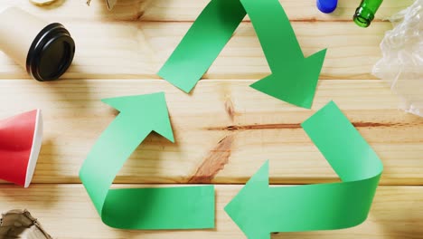 cierre de la basura y el símbolo de reciclaje de flechas de papel verde sobre fondo de madera