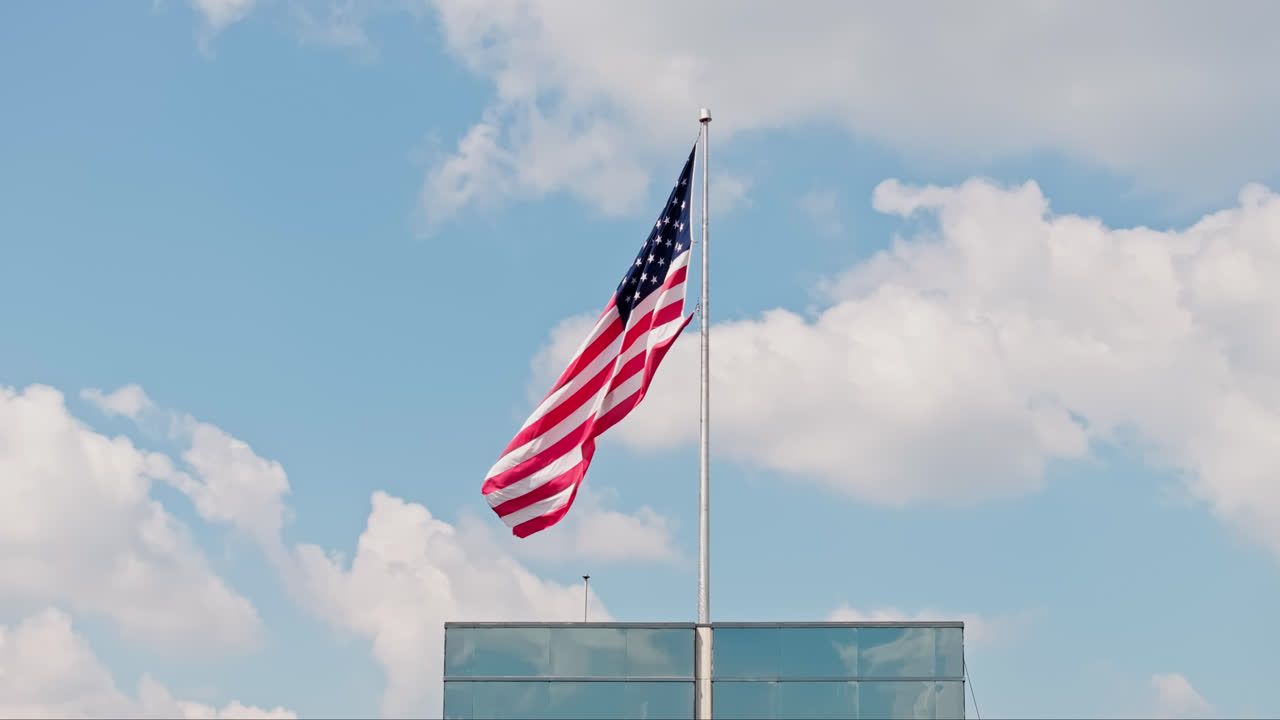 Bandiera americana su pennone davanti a un lussuoso grattacielo contro un cielo con nuvole