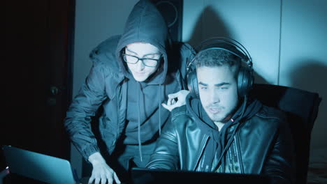 two young guys talking and discussing while hacking in dark room late at night