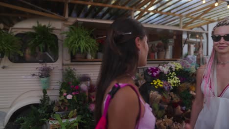 two women conversing at a flower market