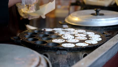 a tray of cooked eggs being scooped out and served into a take away box at a street food stall in borough market, london
