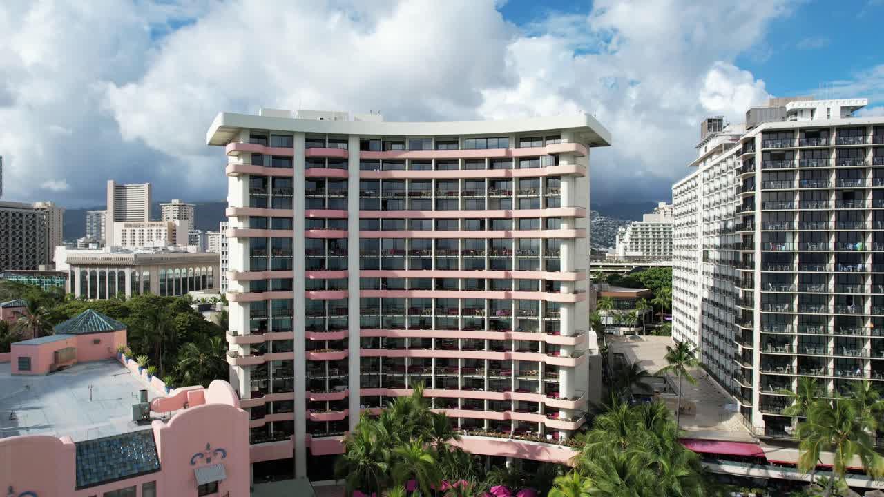 un dron comienza a acercarse a un hotel y vuela hacia atrás para revelar familias de vacaciones en la playa y surfistas surfeando