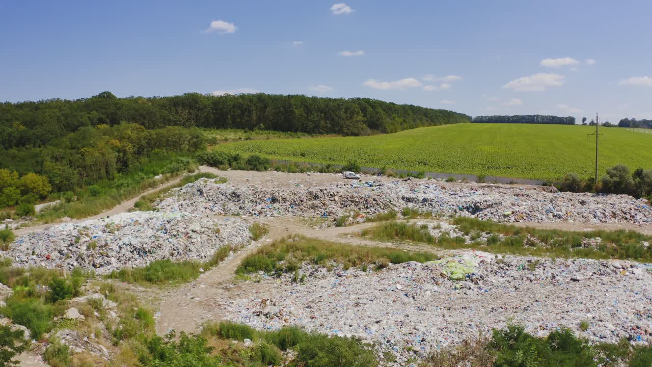 Garbage among nature. Piles of rubbish on field surrounded by green trees. Pollution of environment. Dirty litter in summer. Aerial view.
