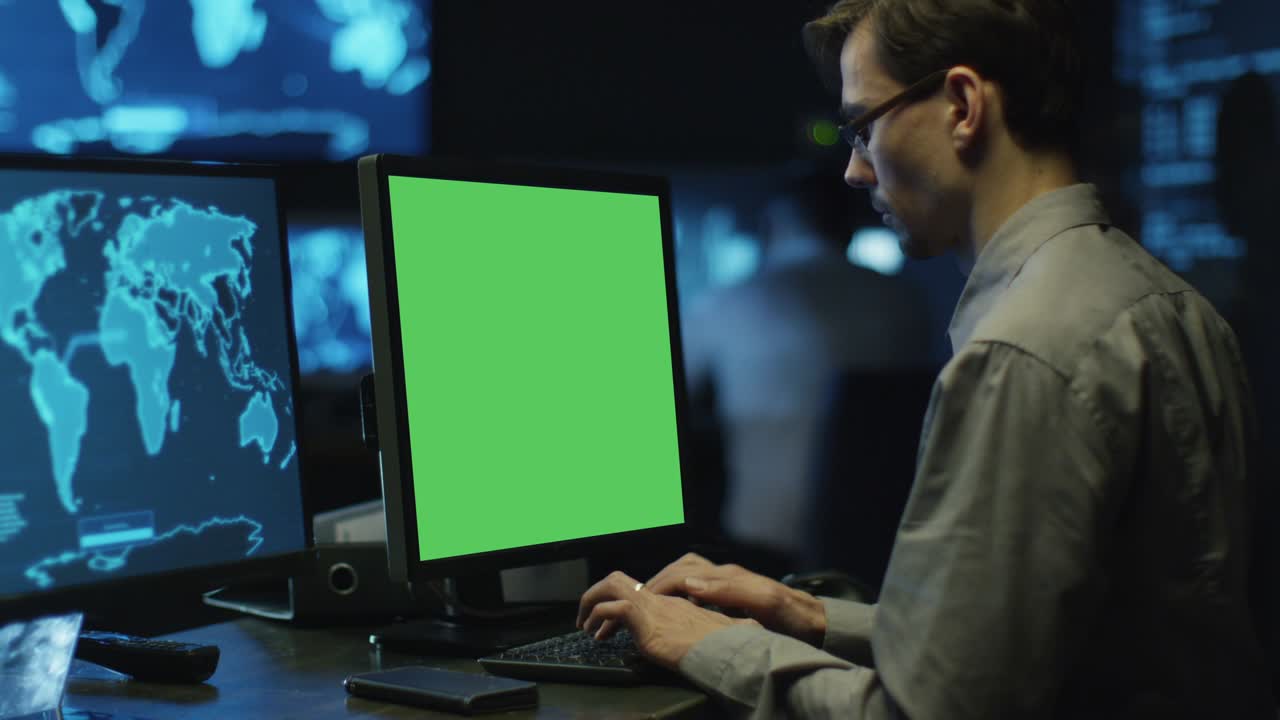 los programadores concentrados trabajan en computadoras personales ubicadas en una sala de control del sistema. la computadora tiene pantalla verde.