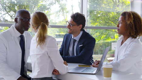 medical team having meeting sitting around table in hospital