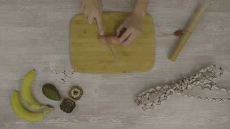 cortando una salchicha en una mesa de madera