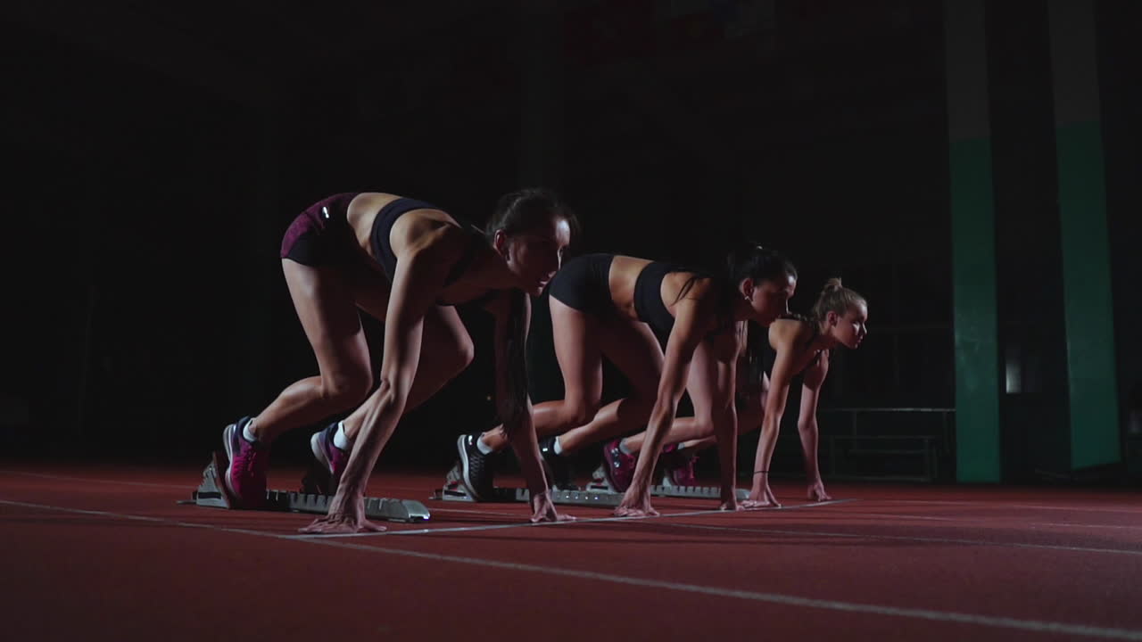 atletas femeninas calentándose en la pista de atletismo antes de una carrera. en cámara lenta