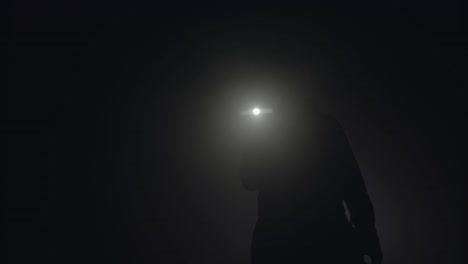 person walking in fog at night with flashlight