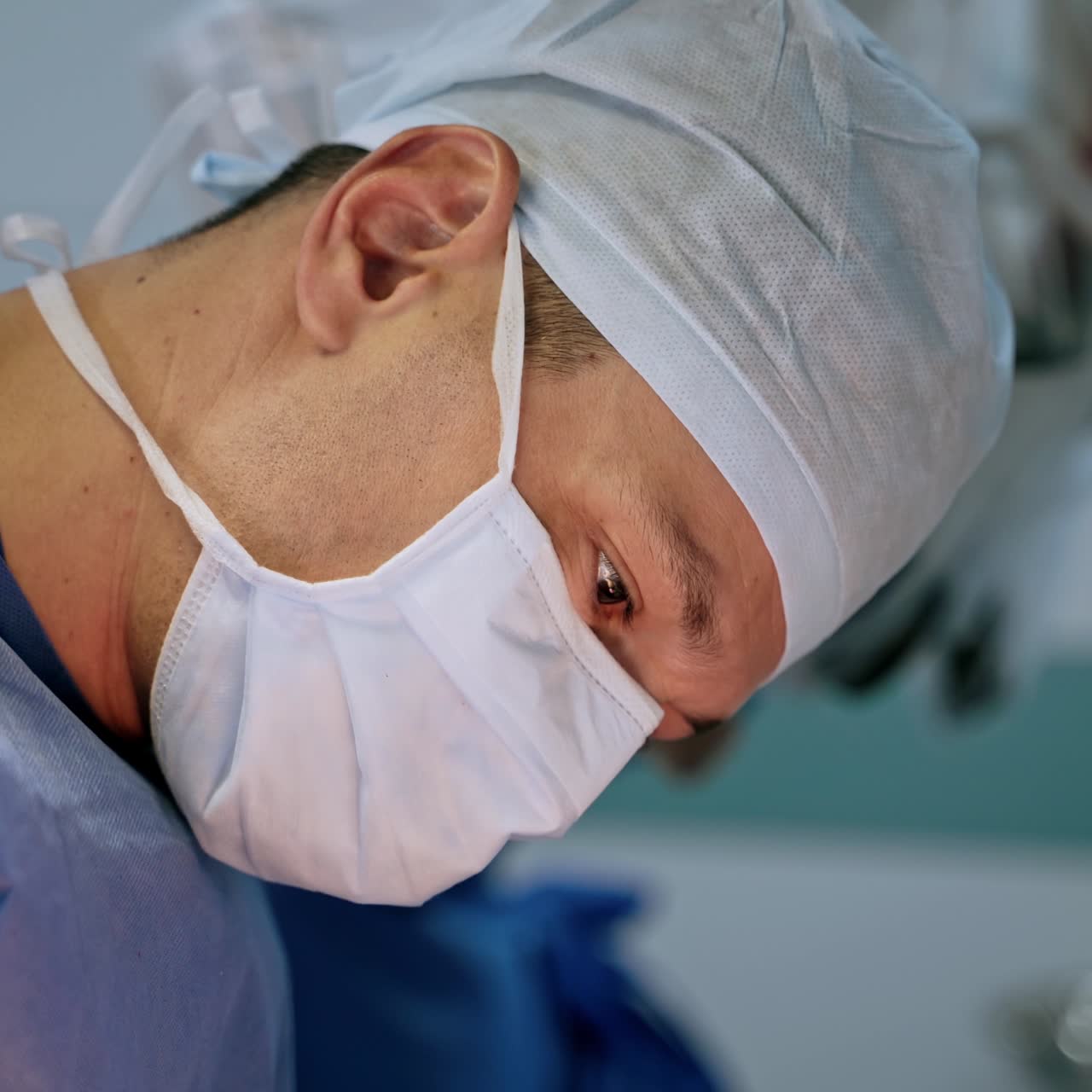 Portrait of a male surgeon in mask. Professional doctor in a hospital operating theatre wearing a surgical cap and mask. Healthcare concept.
