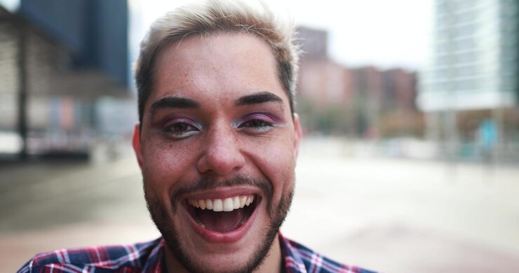 Primo piano di un giovane uomo sorridente con trucco