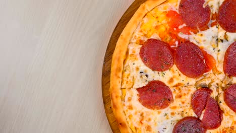 half of slicing salami pizza on wooden board on the table.