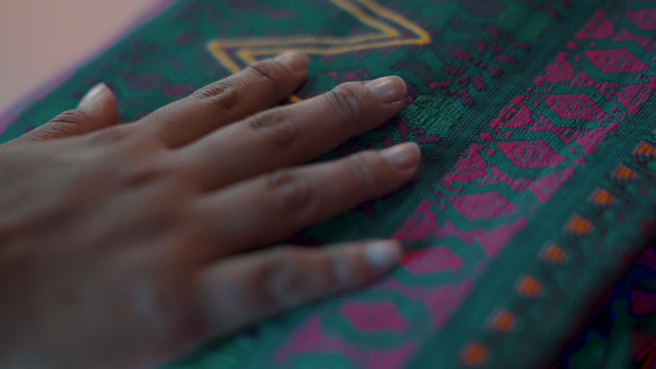 mano de mujer maya tocando un colorido textil guatemalteco hecho a mano