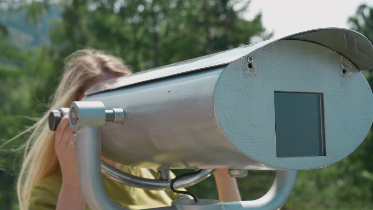 леди смотрит через мощный бинокль, стоя на точке.