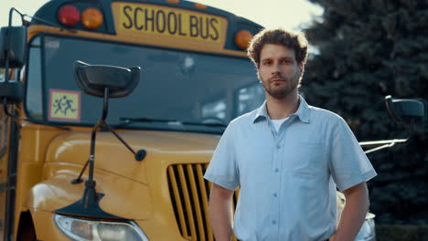 portrait schoolbus driver standing at yellow vehicle alone looking camera.