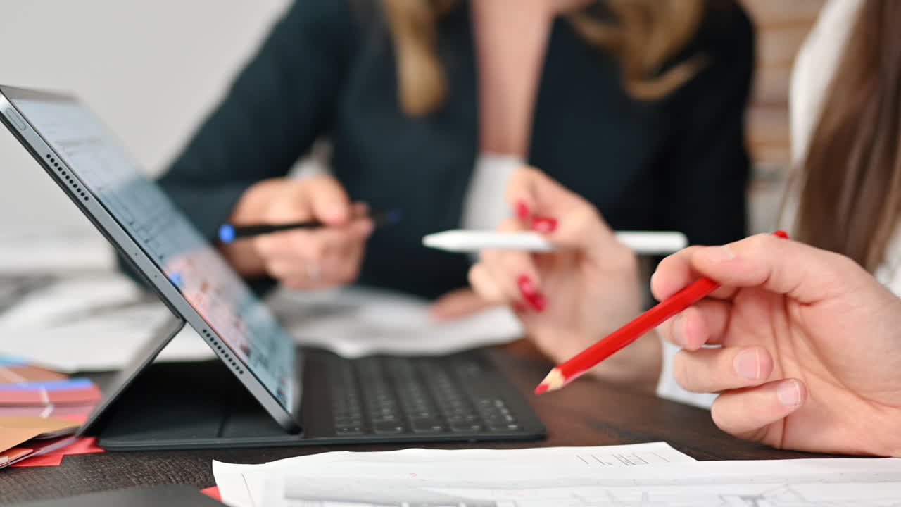 Kollegers analyse af en byggeplan på en tablet ved et bord på et kontor