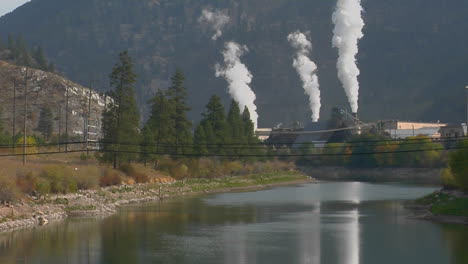 Smoke Comes Billowing Out Of A Factory Along A Waterway