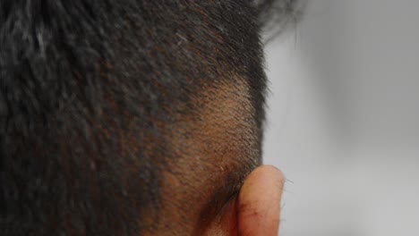 a barber clean fading side of other mans hair with hair clippers, shaving right to the skin