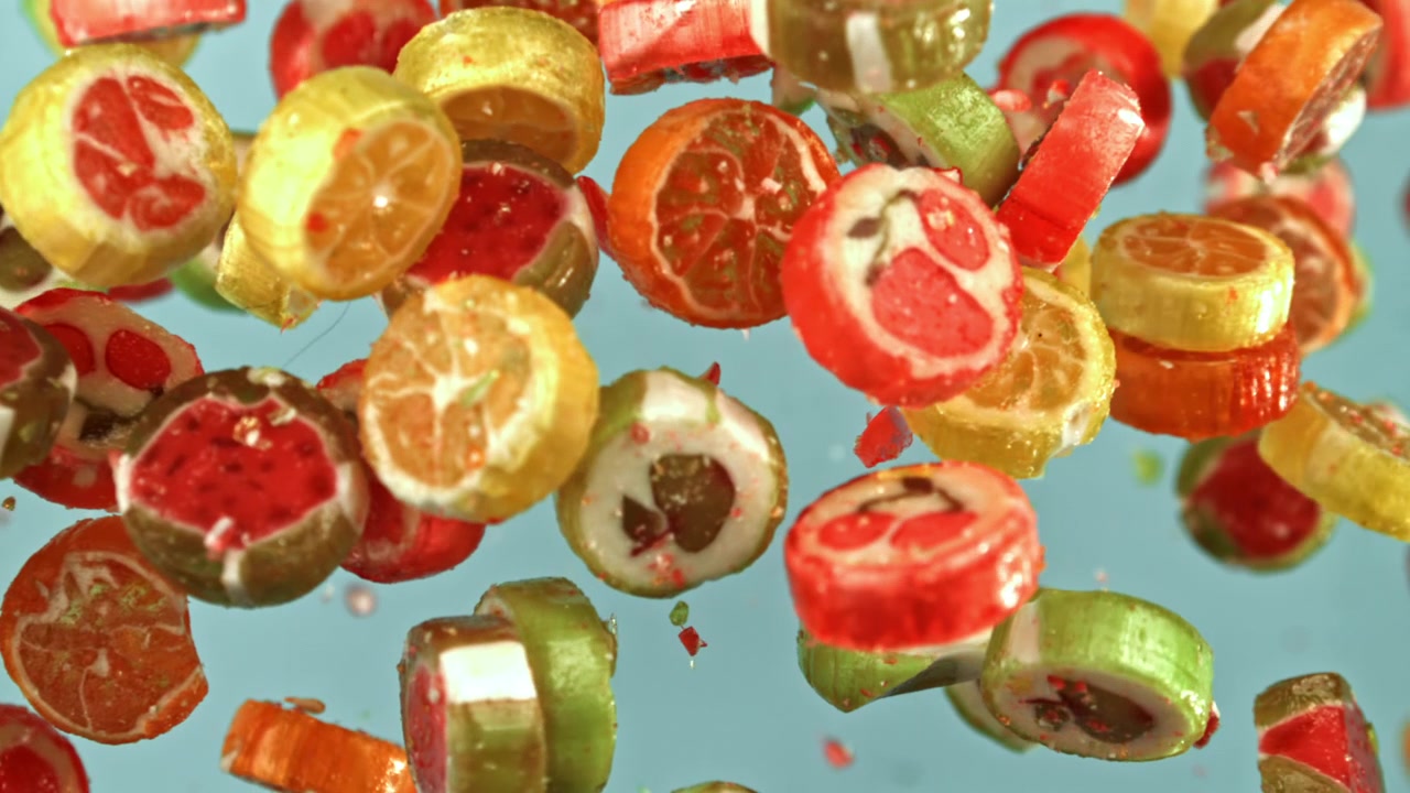 Bunte Fruchtbonbons fallen in Zeitlupe auf blauem Hintergrund