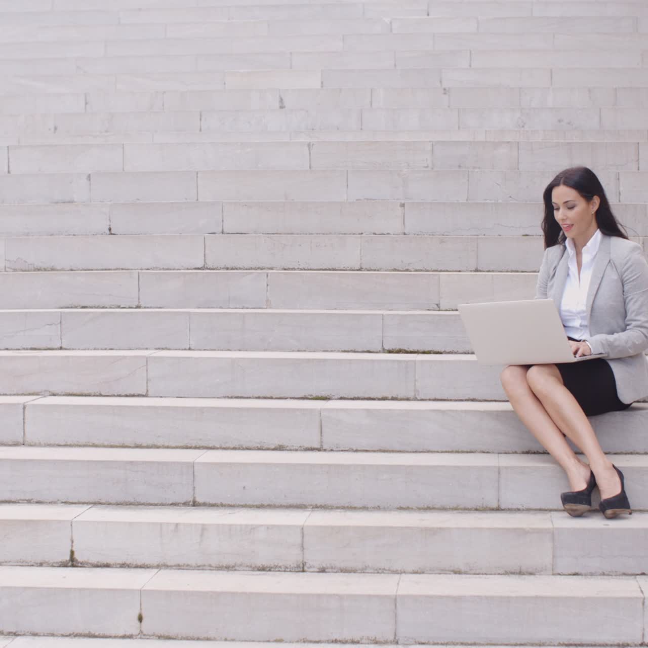 bastante joven trabajador sentado en los pasos con la computadora portátil