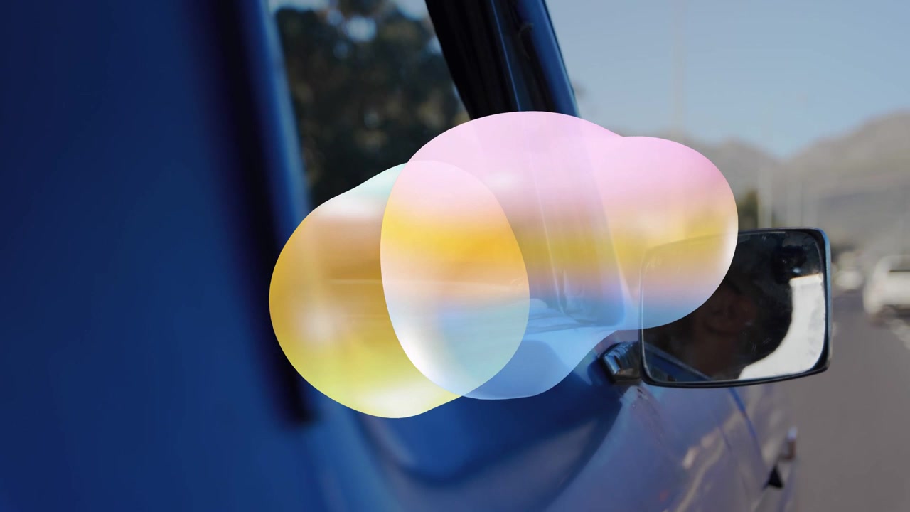 Sich bewegendes Fahrzeug, das farbige, sich verformende Flecken erzeugt, die die Spiegelung des Fahrers teilweise bedecken.