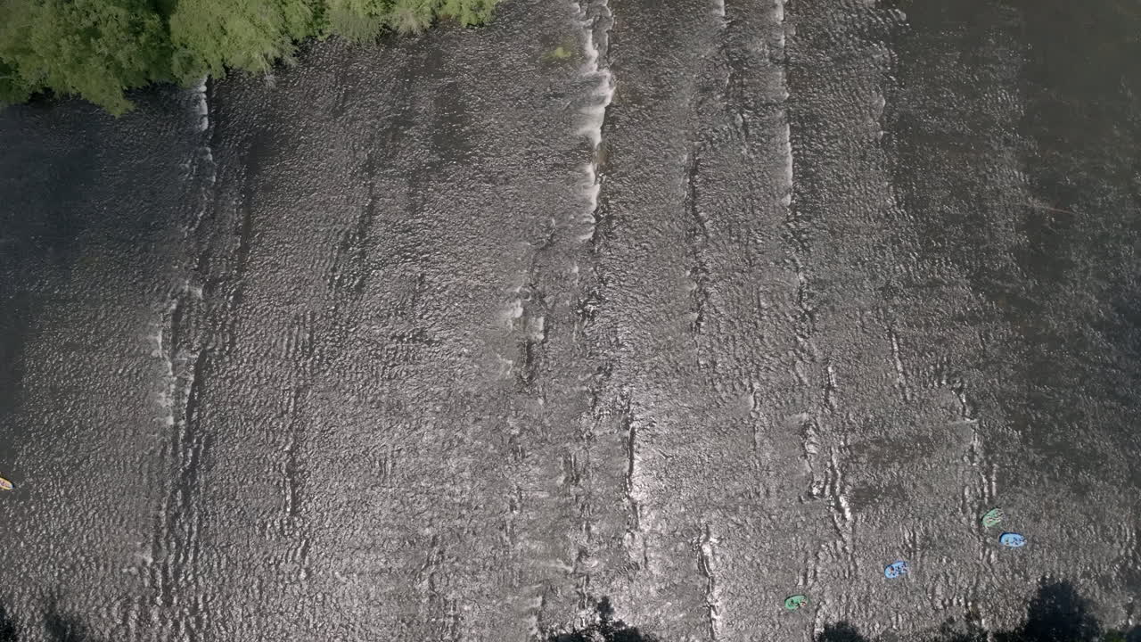 Static top down aerial footage of the Hiawassee River with tourists in inner tubes floating on it.