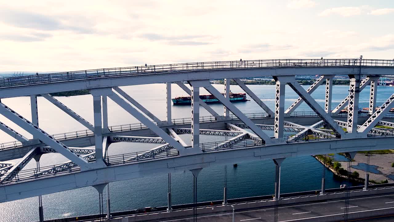 Close-up flyover of Bayonne bridge approaching cargo ship from afar near New York City - rising approach aerial footage