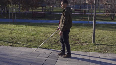 a blind man in a coat walking in the park in autumn.