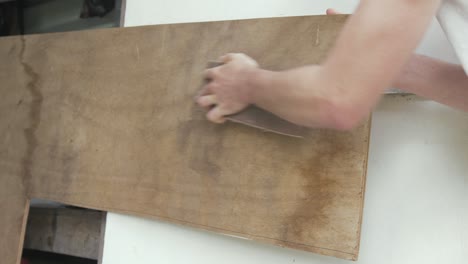 Carpenter-sanding-plywood-with-sandpaper