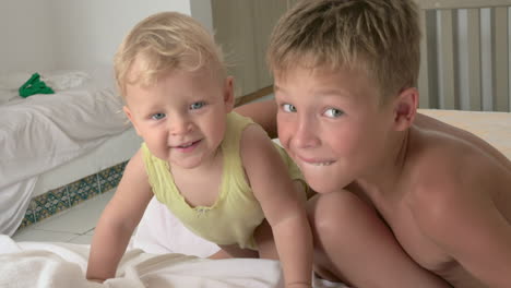 a baby girl and her elder brother playing on mattresses