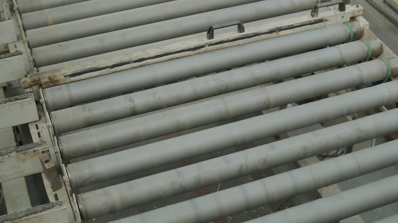 Assi di legno che si muovono lungo un nastro trasportatore in una fabbrica.