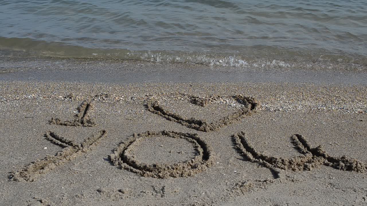 Inscription on the beach. Shooting on the beach. Shooting on the beach