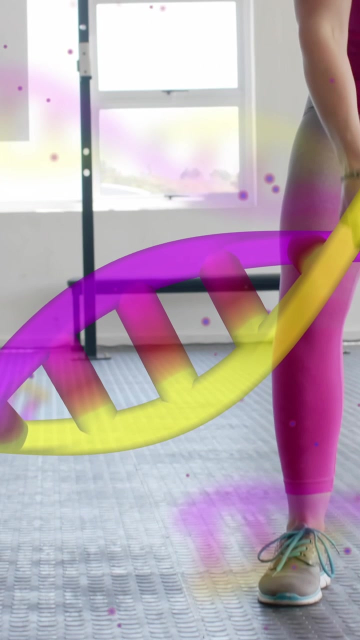 Animation of dna strands over happy caucasian woman cross training with battle ropes at gym
