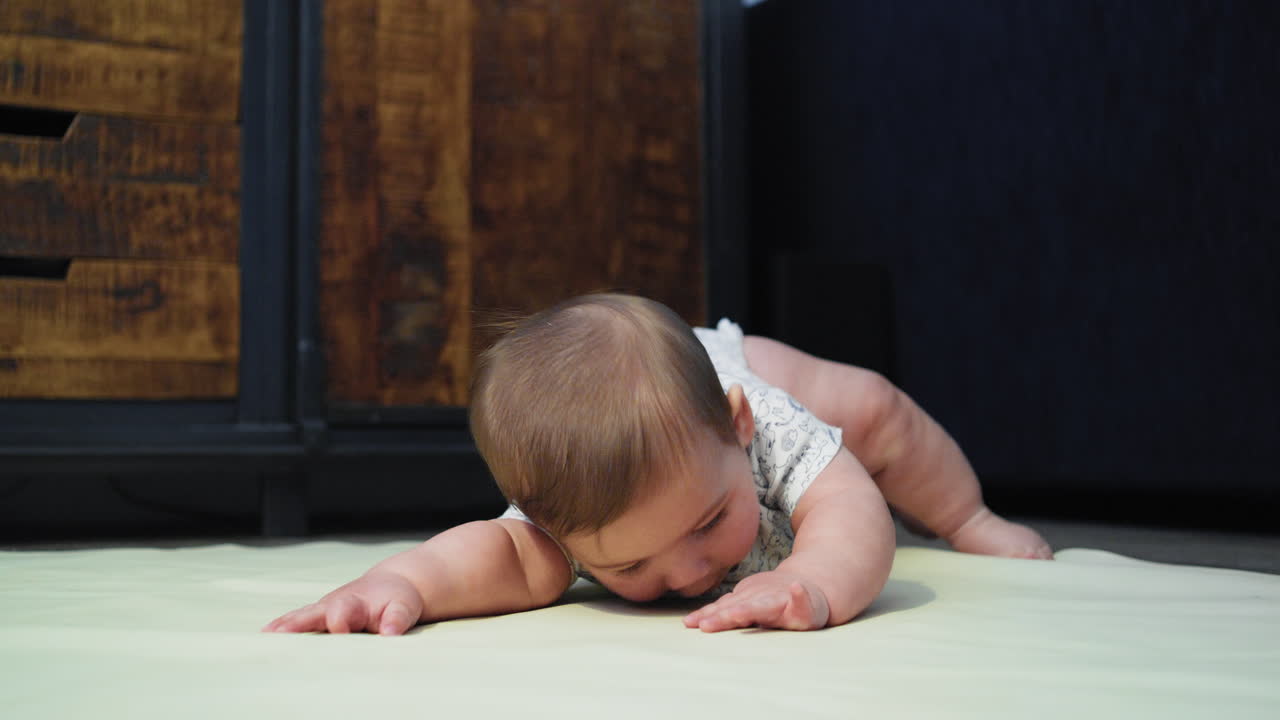 bebé sonriendo en el suelo mientras está en su estómago aprendiendo a arrastrarse