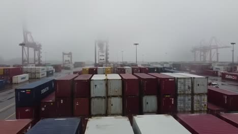 a foggy cargo terminal scene: shipping containers stacked amidst misty conditions at a busy port, highlighting the industrial activity and logistics operations