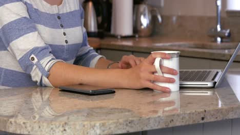 mujer asiática usando su computadora portátil tomando café