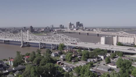 aerial pull-back shot revealing the louisville, kentucky skyline and several bridges spanning the ohio river. great for cityscape, infrastructure, and travel content.