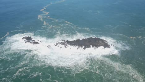 Aerial-view-of-big-waves-breaking-on-the-coral-rocks-in-the-sea---4K-drone-shot