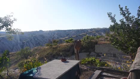 relaxed rural life, pan from wooden chair and table in garden to beautiful landscape in uchisar, cappadocia, turkey