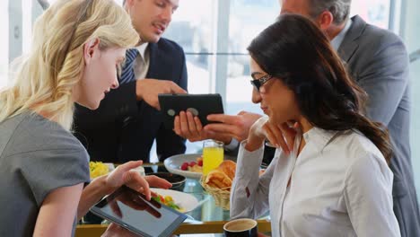 four smiling people watching their tablet