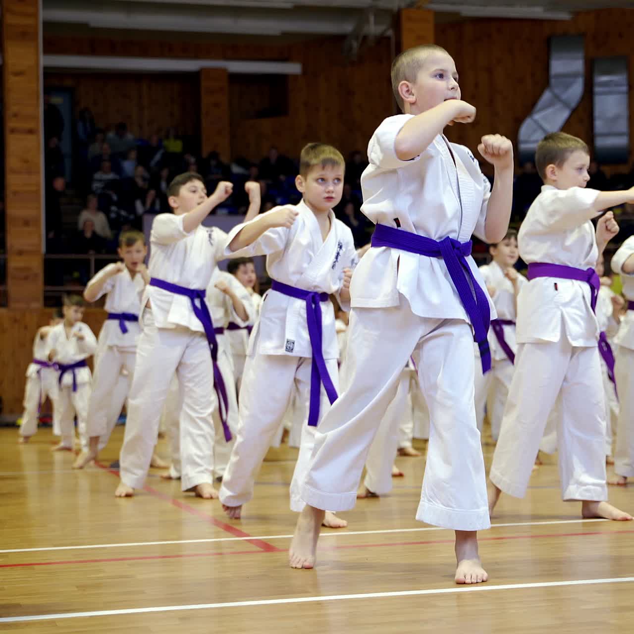 Young athletes in white kimonos practice punches with hands. Children working out the kicks in the big gym