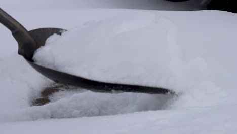 una toma en cámara lenta de una pala quitando nieve de una acera delantera