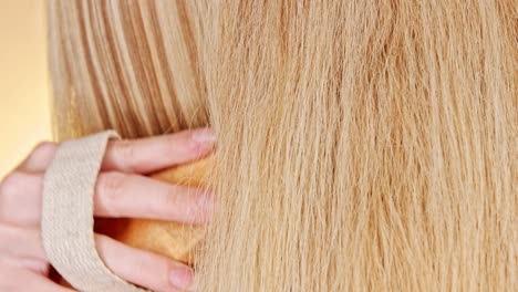 primer plano del cabello rubio liso de una mujer joven mientras se cepilla el cepillo natural