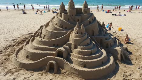 an impressive sandcastle masterpiece built on the beach showcasing castle towers, intricate designs, and architectural features amidst beachgoers enjoying the sun