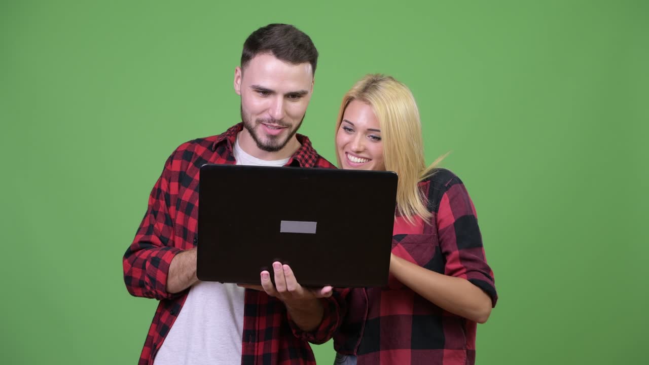 Young happy couple smiling while using laptop together